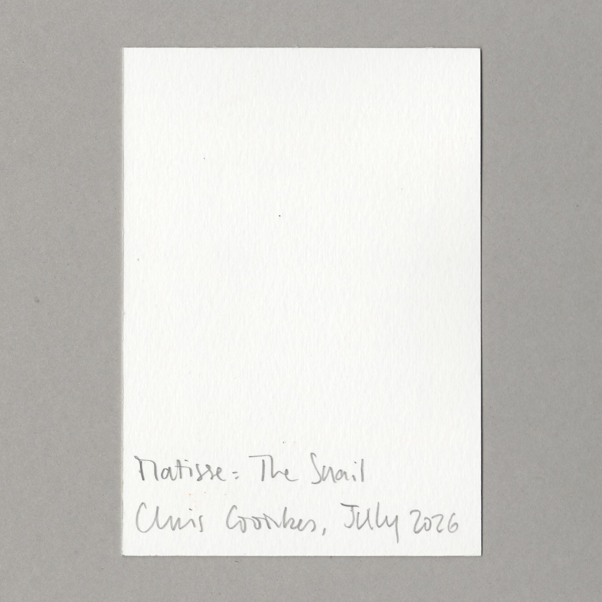 A white rectangular card with handwritten text at the bottom reading 'Matisse: The Snail Chris Coombes, July 2026', photographed against a plain grey background.