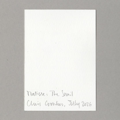 A white rectangular card with handwritten text at the bottom reading 'Matisse: The Snail Chris Coombes, July 2026', photographed against a plain grey background.
