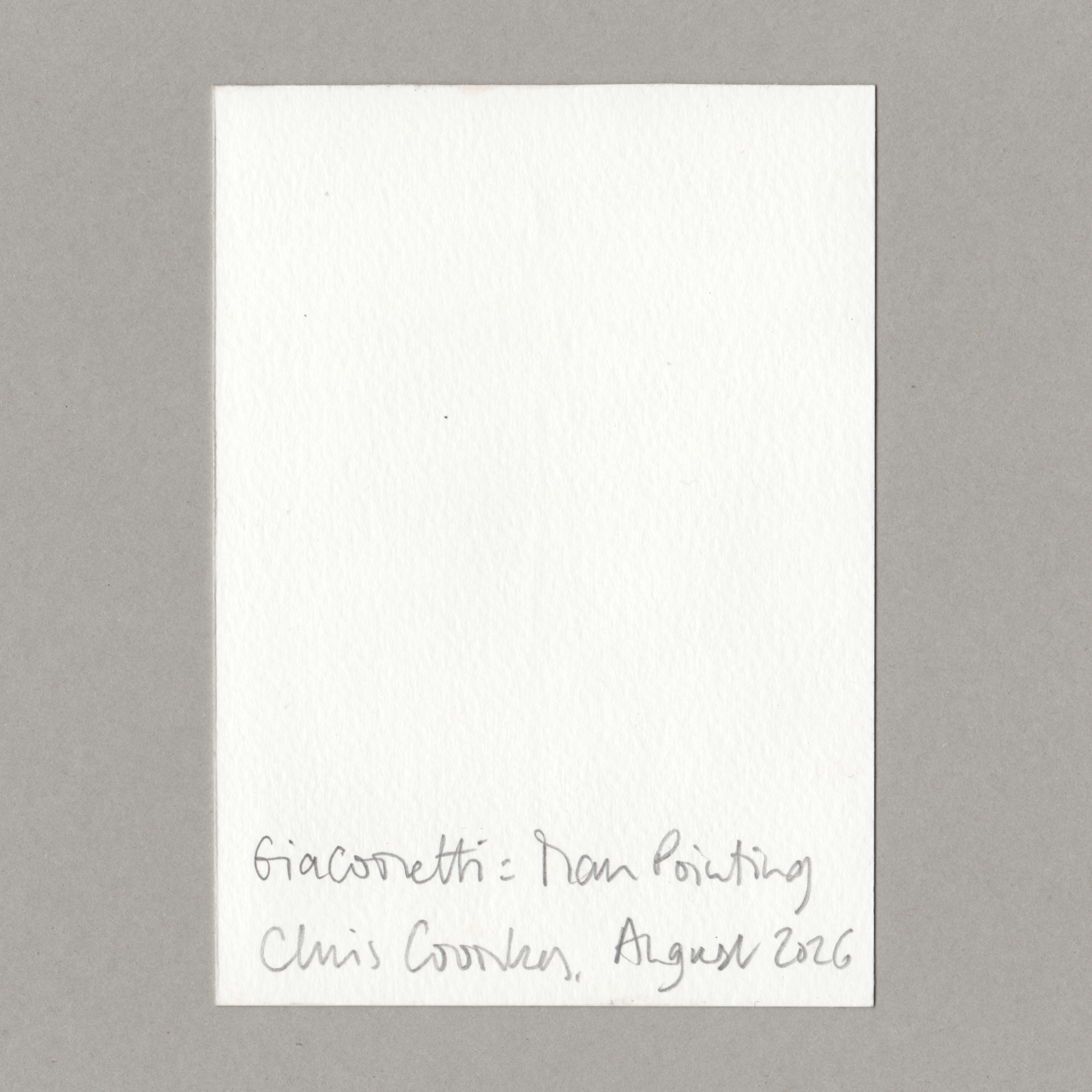 A small white rectangular paper card with handwritten text at the bottom reading 'Giacometti - Man Pointing Chris Coombes, August 2026', photographed against a plain grey background.