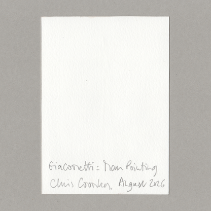 A small white rectangular paper card with handwritten text at the bottom reading 'Giacometti - Man Pointing Chris Coombes, August 2026', photographed against a plain grey background.