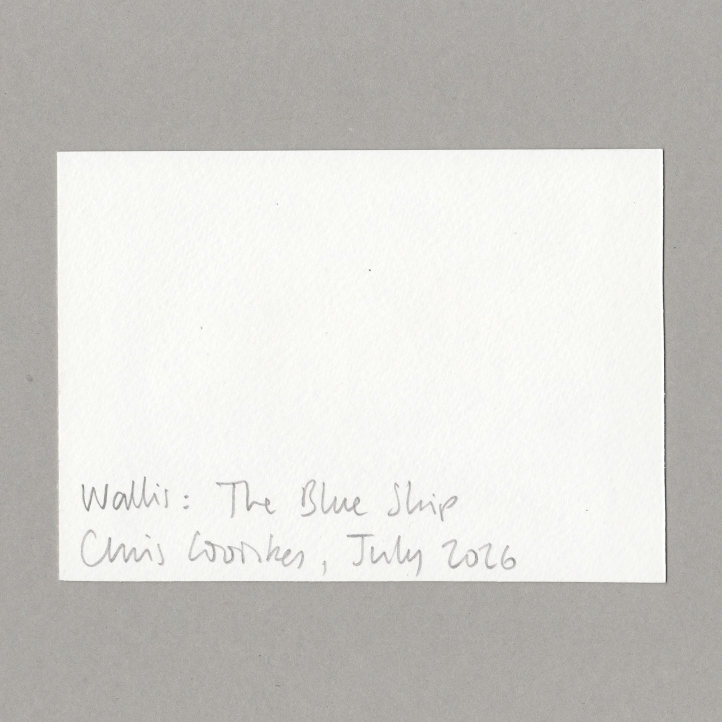 A white rectangular card with handwritten text at the bottom reading 'Walli: The Blue Ship Chris Cowles, July 2026', photographed against a plain gray background.