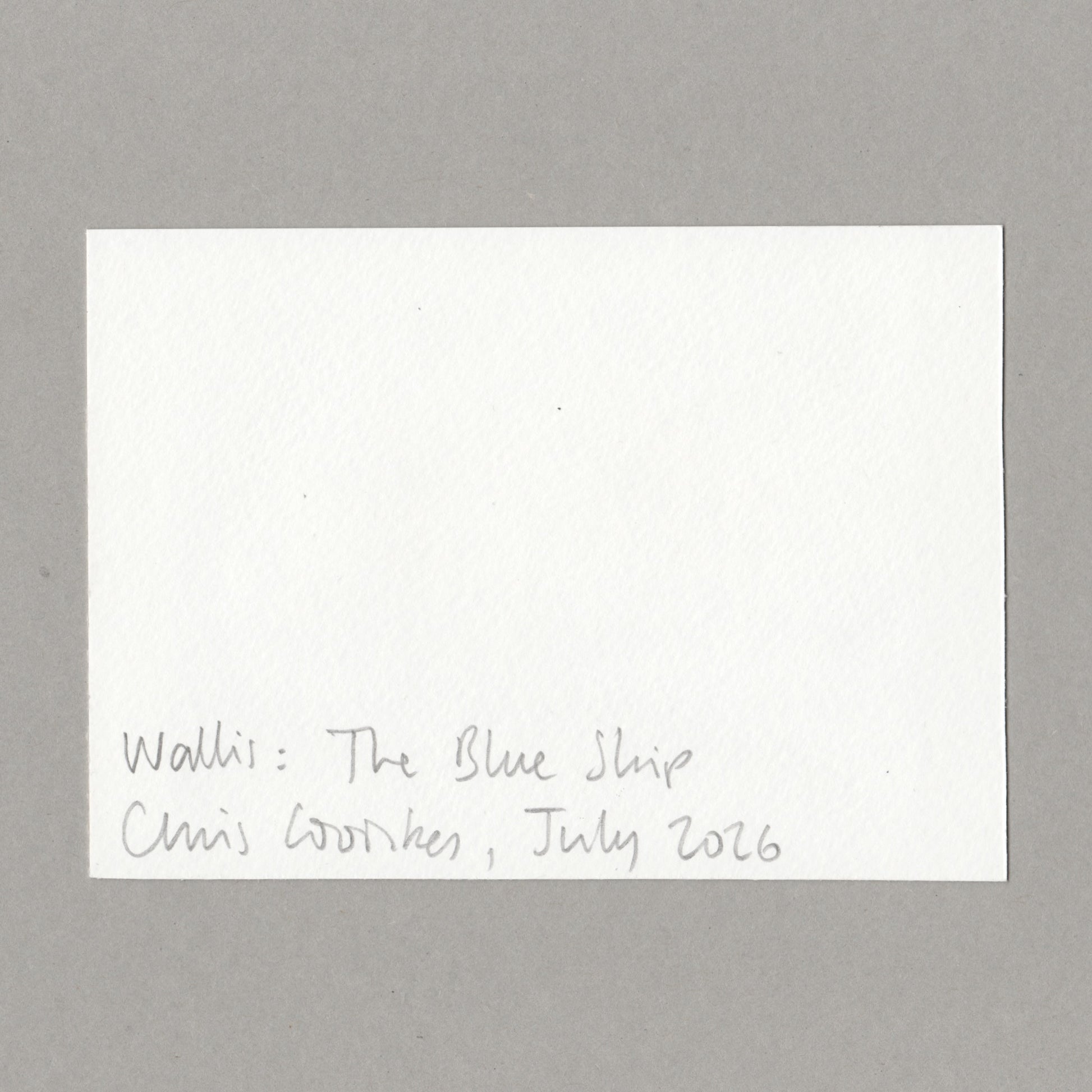A white rectangular card with handwritten text at the bottom reading 'Walli: The Blue Ship Chris Cowles, July 2026', photographed against a plain gray background.